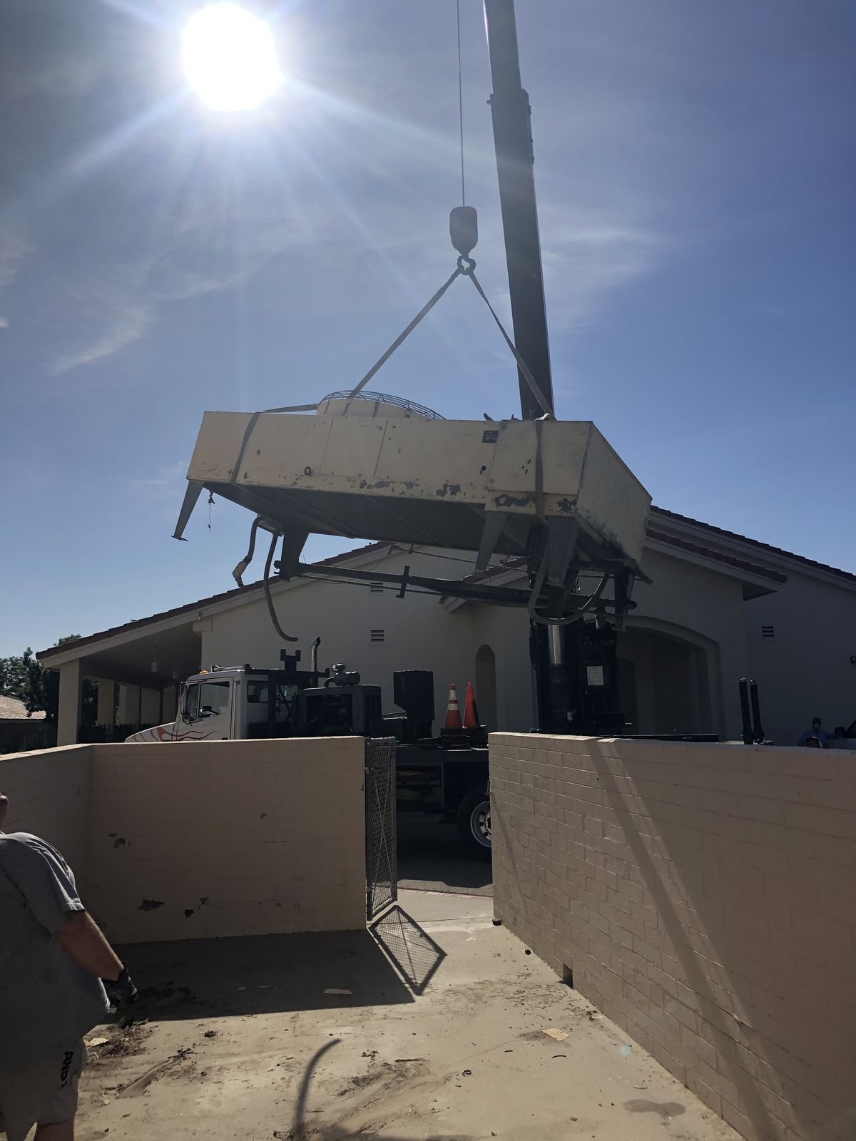 Crane lifting a rooftop HVAC unit onto a commercial building